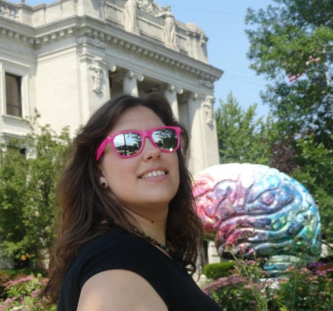 Michelle in pink glasses and a multicolored brain in the background. 